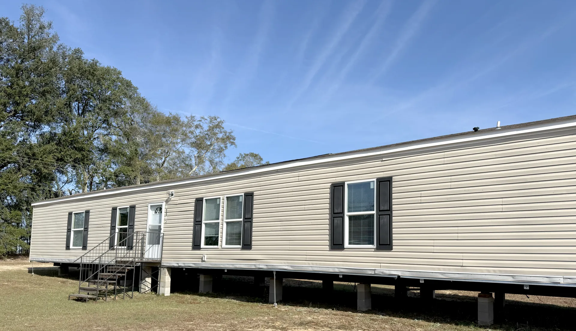 2019 Clayton Breeze southern family home exterior with tan vinyl siding and black shutters